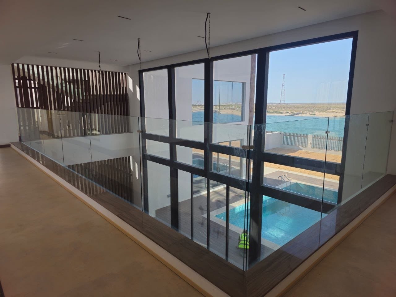 Interior mezzanine with glass balustrade and glazing over the pool and sea