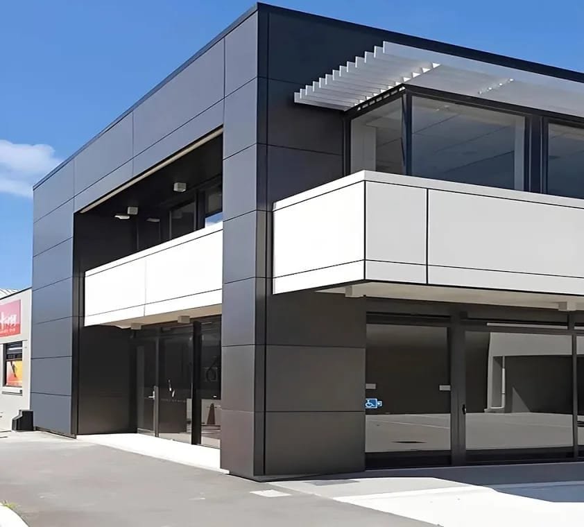 Modern commercial building with black-and-white aluminum cladding and a glass storefront